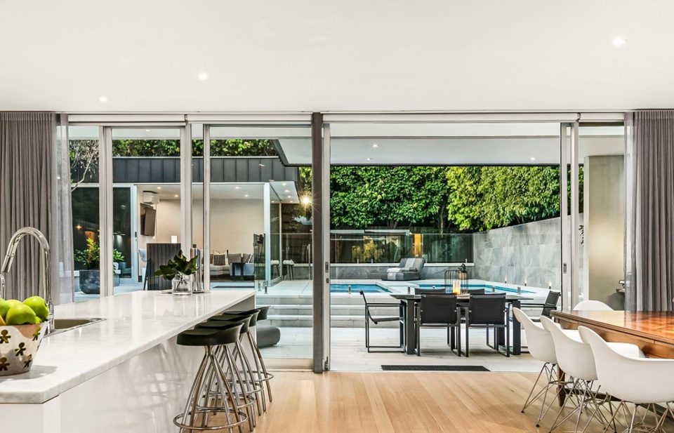 View from the kitchen through open glazing to the pool terrace