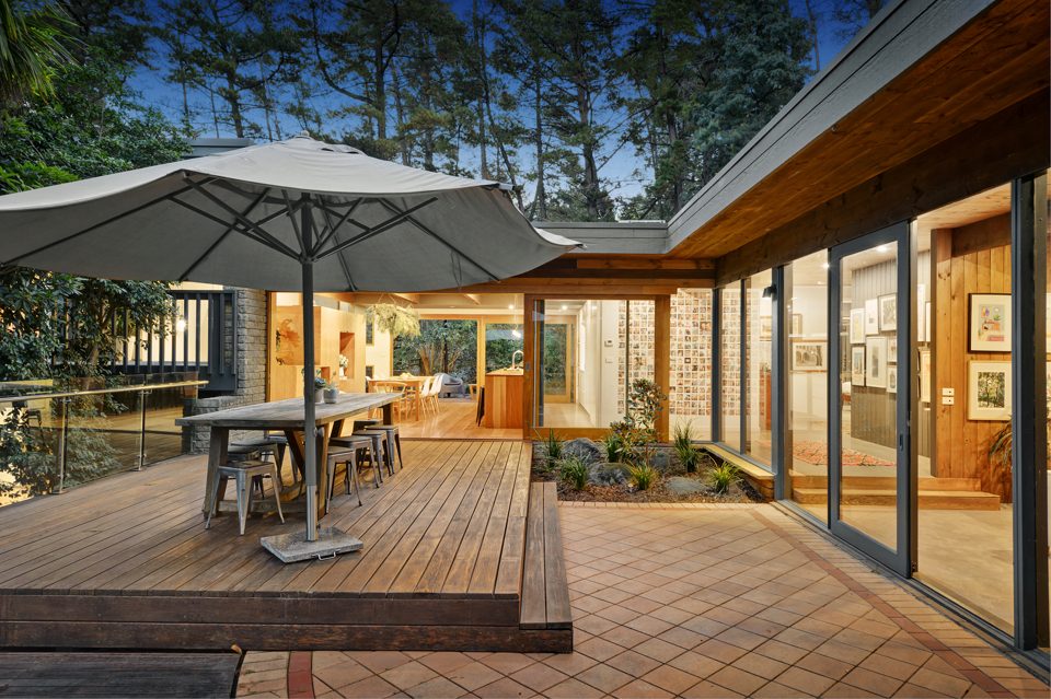 Timber deck with market umbrella wrapped by the house and garden