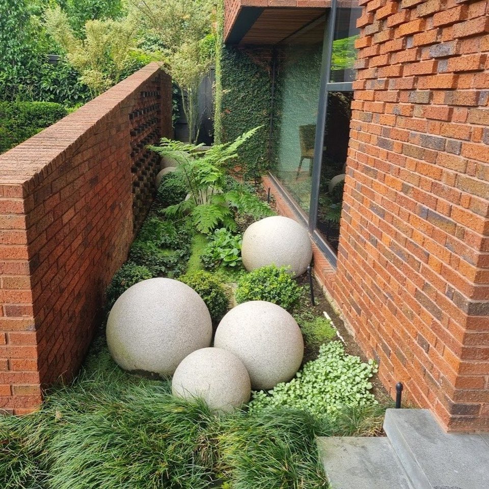 Cast concrete spheres in mondo grass against red brickwork