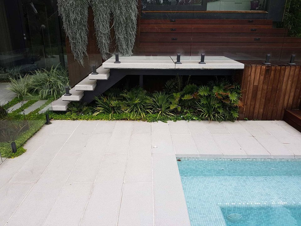 Floating concrete steps over dense understorey planting beside a spa