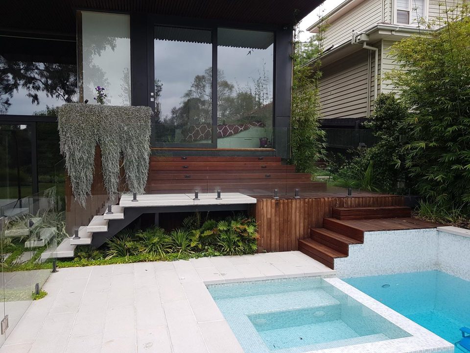 Pool with timber deck, dark timber walls and cascading planting